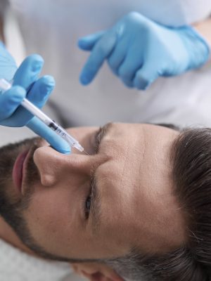 Middle aged man grimaces of pain while skilled cosmetologist does injection